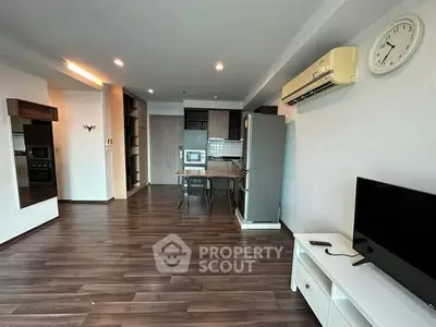 Spacious modern living room with open kitchen, featuring sleek wooden flooring and contemporary furniture.