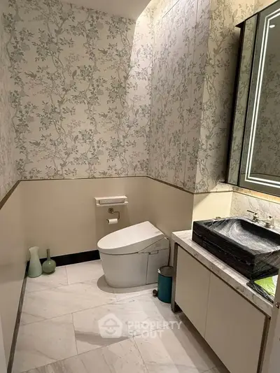 Luxurious bathroom with elegant wallpaper and modern fixtures, featuring a sleek toilet and stylish vanity.