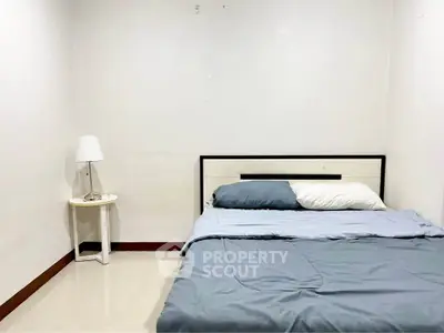 Minimalist bedroom with cozy bed and modern lamp on side table.