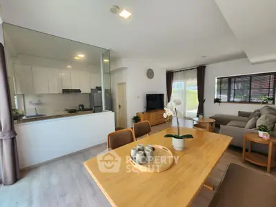 Modern open-plan living room with dining area and kitchen, featuring stylish decor and natural light.