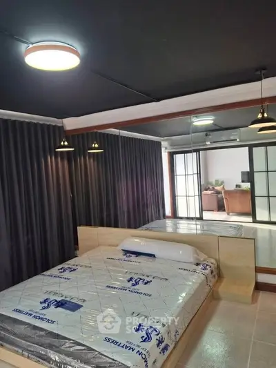 Modern bedroom with sleek design and large mirror reflecting natural light.