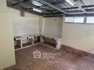 Spacious kitchen with tiled countertops and ample natural light, perfect for culinary enthusiasts.