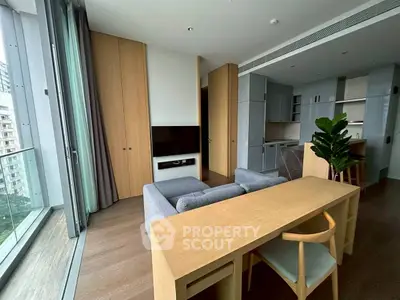 Modern living room with open kitchen and balcony view in urban apartment.
