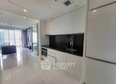 Modern open-layout kitchen with sleek cabinetry and integrated appliances in a bright apartment.