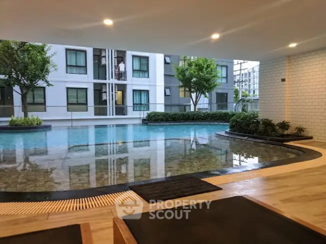 Modern apartment complex with serene pool view and lush greenery.