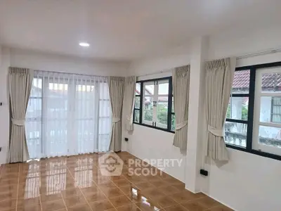 Spacious living room with large windows and elegant curtains, featuring glossy tiled floors.