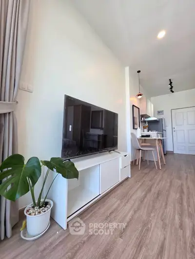 Modern living room with stylish decor and open kitchen layout, featuring a sleek TV stand and elegant flooring.