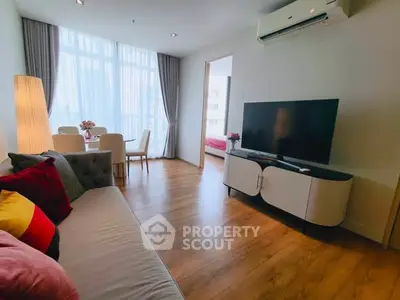 Modern living room with stylish decor and natural light, featuring a cozy sofa and sleek TV setup.