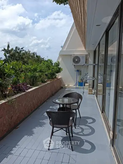 Spacious balcony with outdoor seating and lush greenery, perfect for relaxation and entertaining.