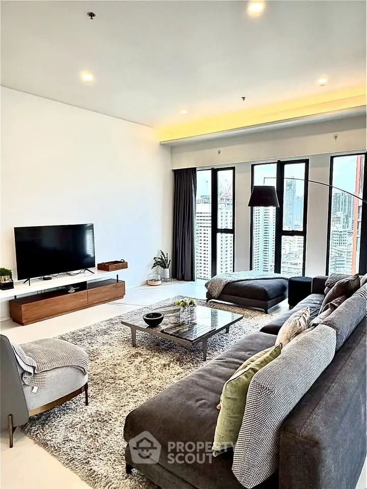 Luxurious modern living room with city view, featuring plush gray sofa and sleek entertainment center.