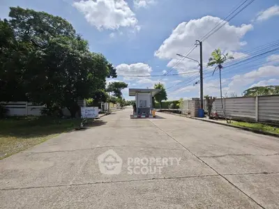Spacious driveway leading to a modern security booth in a serene residential area.