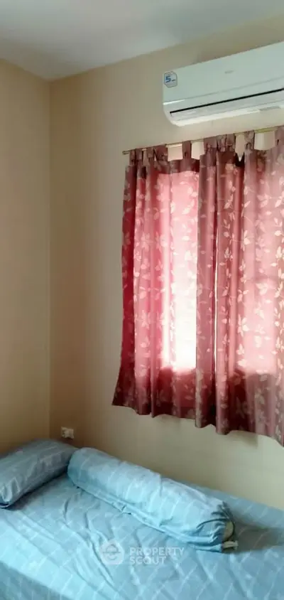 Cozy bedroom with air conditioning and floral curtains, perfect for relaxation.