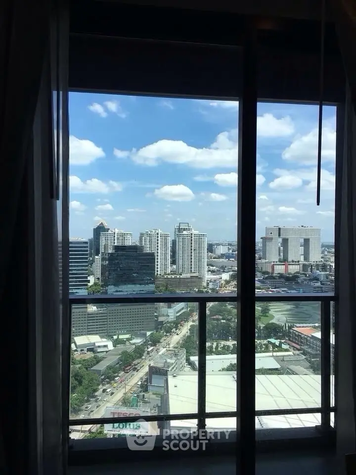 Stunning cityscape view from high-rise apartment window with clear blue sky.