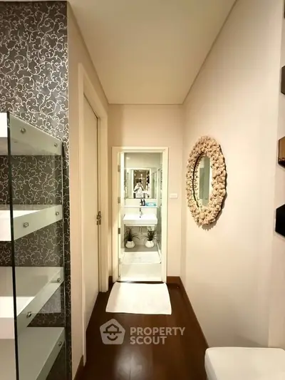 Stylish bathroom with elegant decor and modern fixtures, featuring a unique mirror and wooden flooring.