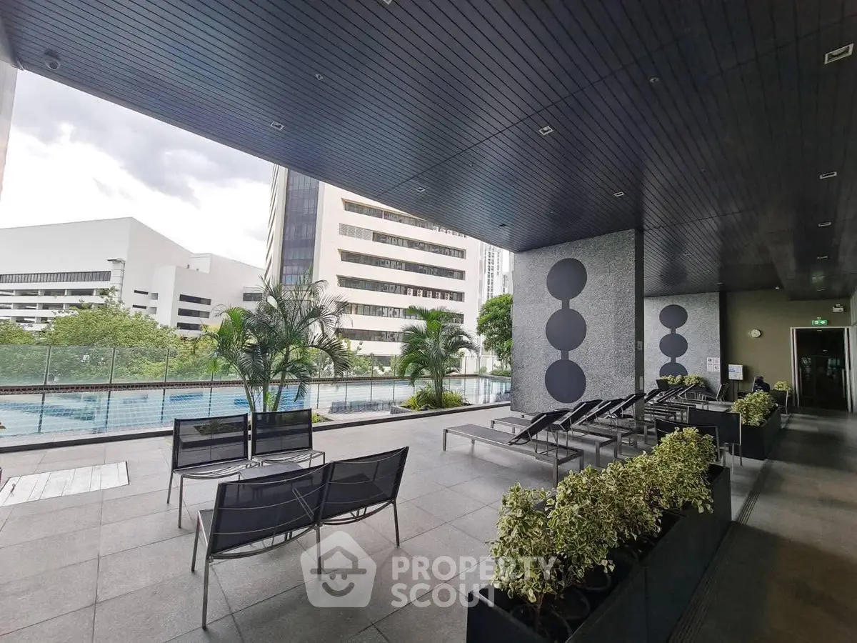 Modern outdoor pool area with lounge chairs and city view, perfect for relaxation and leisure.