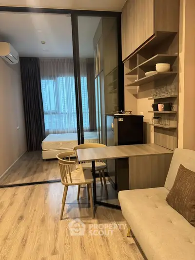 Modern studio apartment with open layout, featuring cozy living area and bedroom separated by glass partition.