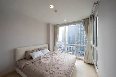 Spacious bedroom with large windows offering stunning city views in a modern high-rise apartment.