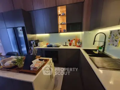 Modern kitchen with sleek cabinetry and island, featuring built-in oven and stylish lighting.