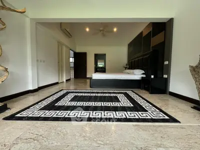 Luxurious bedroom with elegant decor and spacious layout, featuring a stylish rug and modern furnishings.