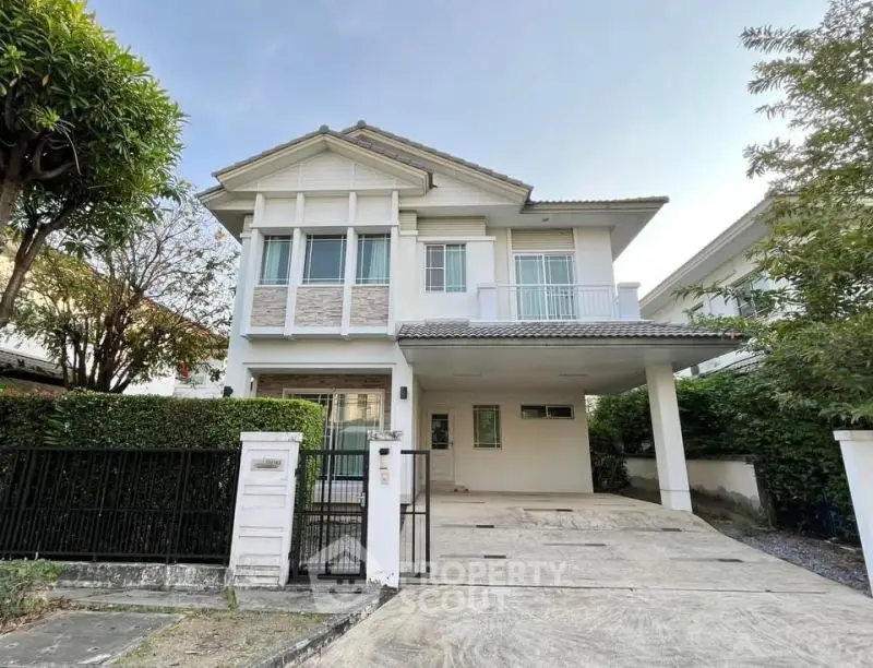 Charming two-story house with spacious driveway and lush greenery, perfect for family living.