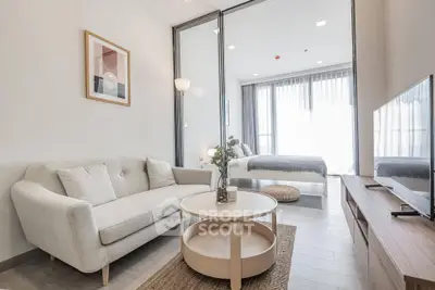 Modern living room with cozy sofa and stylish decor leading to a bright bedroom.