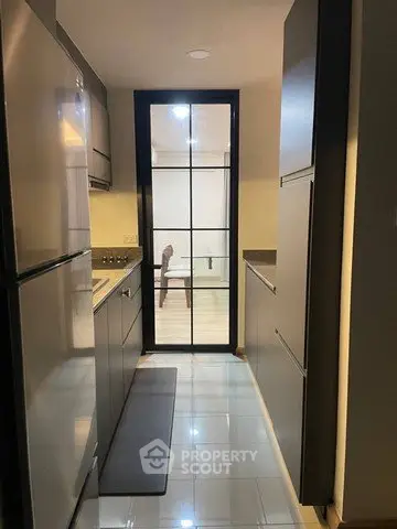 Modern kitchen with sleek cabinetry and glass door leading to dining area