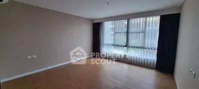Spacious empty room with large window and wooden flooring, perfect for customization.