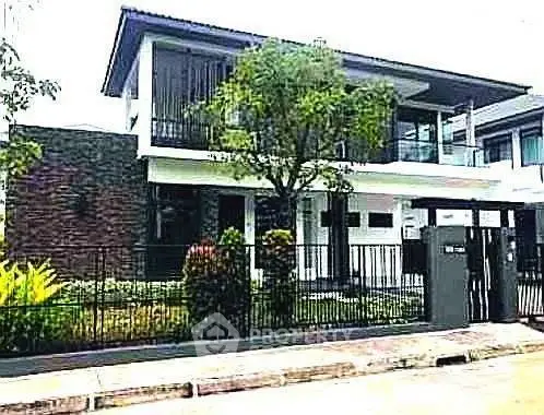 Modern two-story house with sleek design and lush garden in a serene neighborhood.