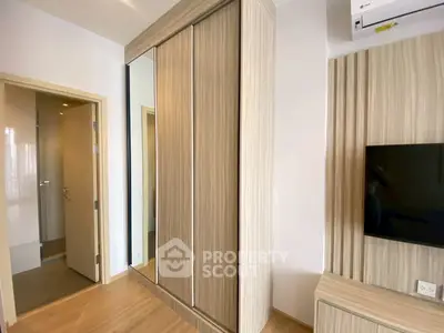 Modern bedroom with sleek wardrobe and mounted TV, showcasing minimalist design.