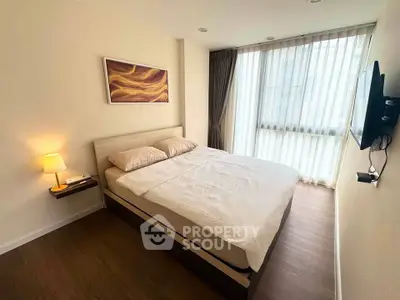 Modern bedroom with cozy bed, wall art, and natural light from large window.