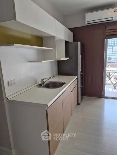 Modern kitchen with sleek cabinetry and stainless steel fridge in a bright apartment.