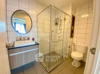 Modern bathroom with glass shower, sleek vanity, and tiled walls in a contemporary home.