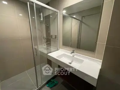 Modern bathroom with sleek shower and elegant sink in contemporary apartment.