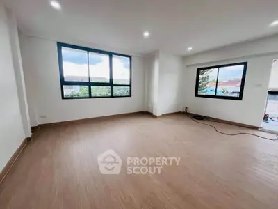 Spacious unfurnished room with large windows and wooden flooring, ideal for customization.