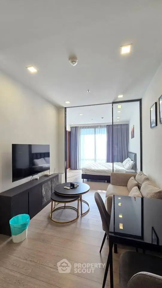 Modern living room with open layout and stylish furniture, featuring a view into a cozy bedroom.