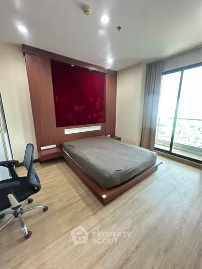 Modern bedroom with wooden flooring and large window offering city views