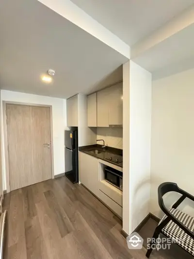 Modern compact kitchen with sleek cabinetry and integrated appliances in stylish apartment.