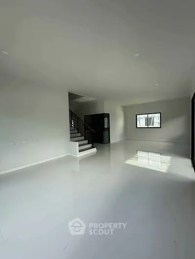 Spacious modern living room with glossy white tiles and staircase, perfect for family gatherings.