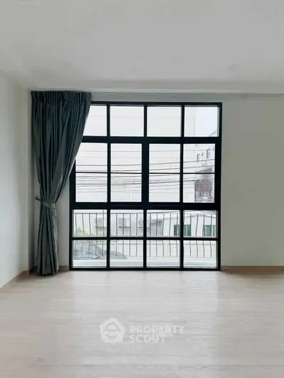 Spacious room with large window and elegant curtains, offering ample natural light and modern design.