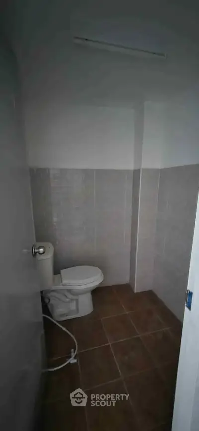 Compact bathroom with tiled walls and floor, featuring a standard toilet.