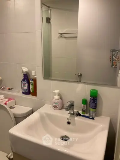 Modern bathroom with sleek sink and mirror, featuring essential toiletries and a clean design.