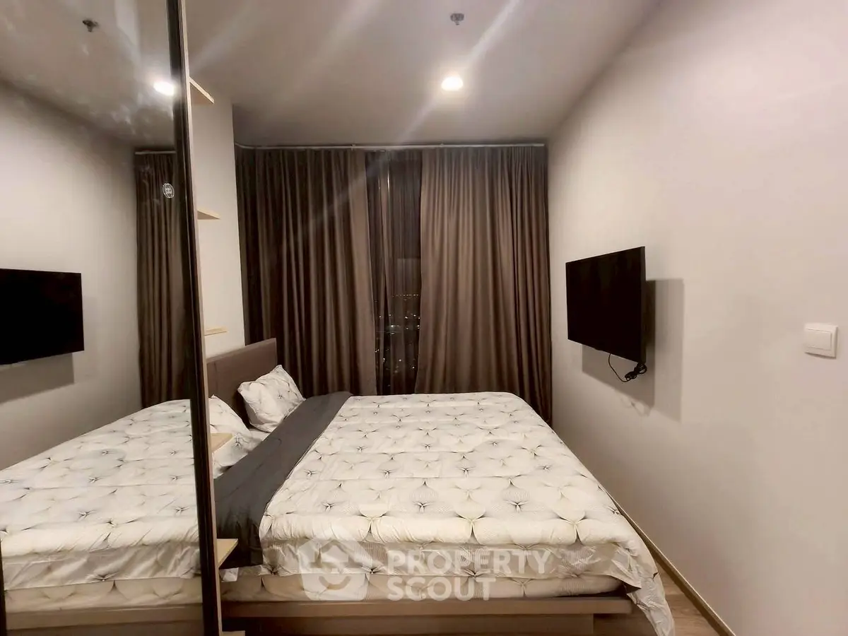Modern bedroom with stylish decor and wall-mounted TV in a cozy apartment.
