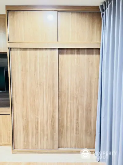 Modern wooden wardrobe with sliding doors in a stylish bedroom setting