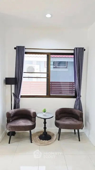 Cozy seating area with two chairs and a window view in a modern home interior.