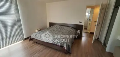 Spacious bedroom with wooden flooring and modern decor, featuring an ensuite bathroom.