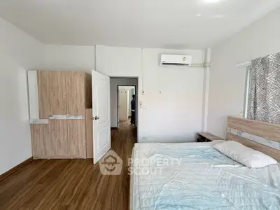 Spacious bedroom with wooden flooring and modern air conditioning unit.