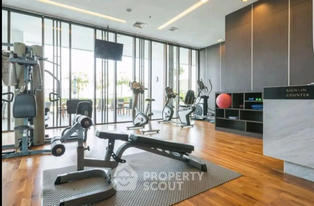 Modern gym with state-of-the-art equipment and wooden flooring in a luxury residential building.