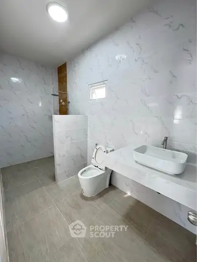 Modern bathroom with sleek white fixtures and marble walls
