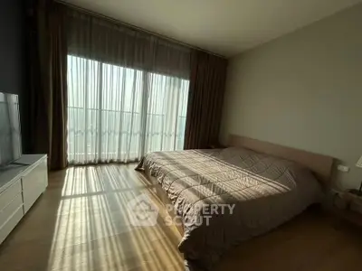 Spacious bedroom with large window and natural light, featuring a cozy bed and modern decor.