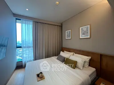 Modern bedroom with large window and stylish decor in urban apartment.